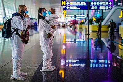 Image: Travellers in protective suits are seen at Wuhan Tianhe International Airport in Wuhan